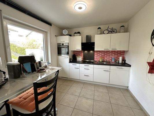 Moderne Einbauküche mit rotem Ziegelrückwand und Tageslichteinfall - Kochen mit Panoramablick!