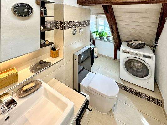 Badezimmer mit schöner Lichtgestaltung und praktischem Waschmaschinenplatz