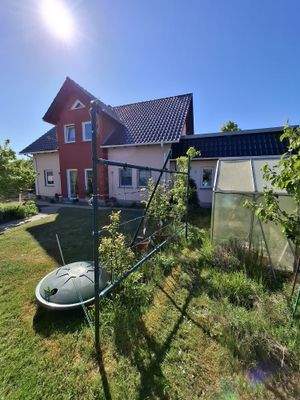 Gewächshaus und Regenwassertank in der Erde