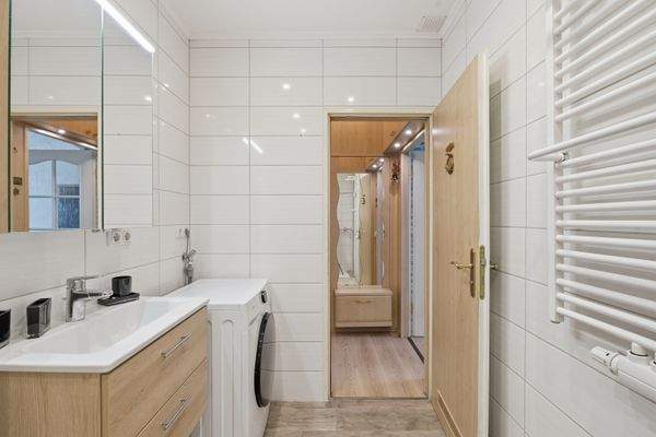 Badezimmer mit breitem Waschtisch, Waschmaschine und Handtuchheizung