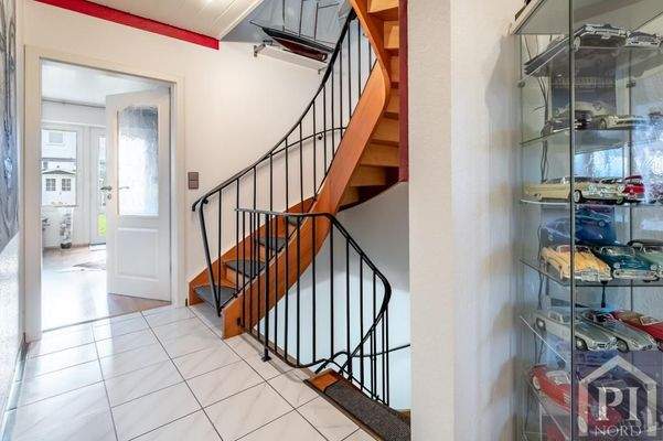 Heller Flur mit geschwungener Holztreppe