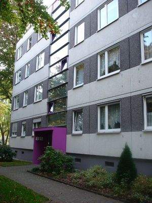 Eingang eines viergeschossigen Wohnhauses mit Bepflanzung