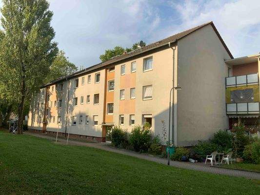 Hausansicht eines Mehrfamilienhauses, umgeben mit Wiese und Bäumen.