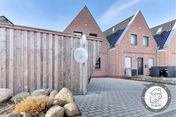 Ansprechende Hausansicht mit Friesenwall und Carportbereich