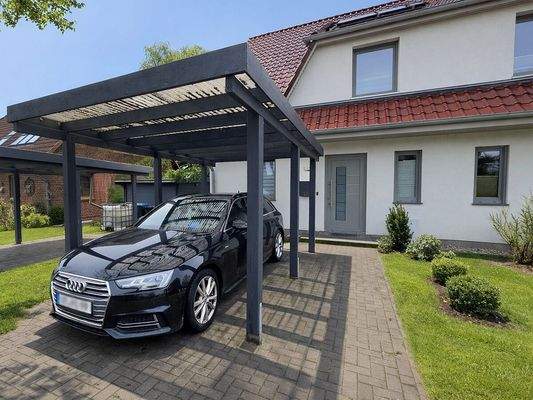 Frontansicht mit den 2 Carports  // KI-Visualisierung – Darstellung im Sommer
