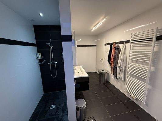 Großes Badezimmer mit Dusche, Badewanne und WC und Schrägfenster. Mit Fußbodenheizung