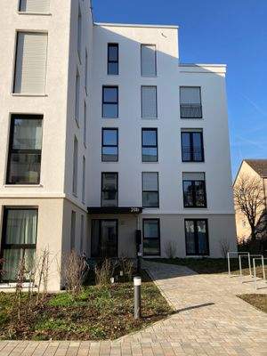 Vorderansicht eines weißen mehrstöckigen Gebäudes mit Fenstern und Hauseingang