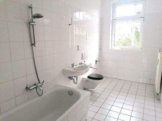 gefliestes Bad mit Wanne und Fenster