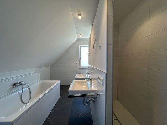 Badezimmer mit großer bodentiefer Dusche, Badewanne, WC und zwei Waschbecken