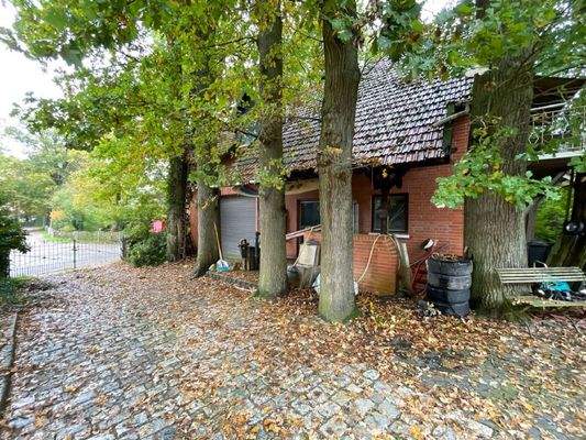 Nebengbeäude unter alten Eichen