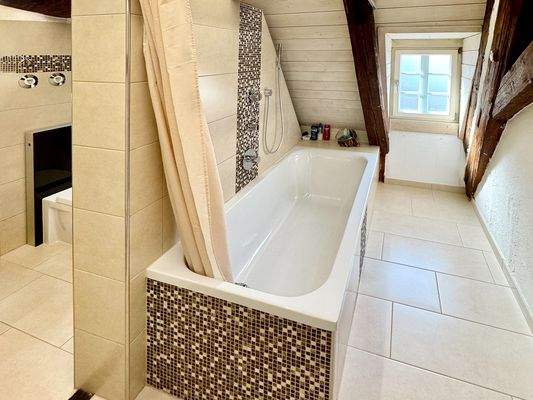 Schöne Aufteilung im hell gefliesten Tageslichtbad mit Badewanne, Waschtisch und WC