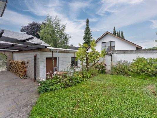 Überdachter Verbindungsbereich zwischen Haus und Garagen – ideal als Holzlager