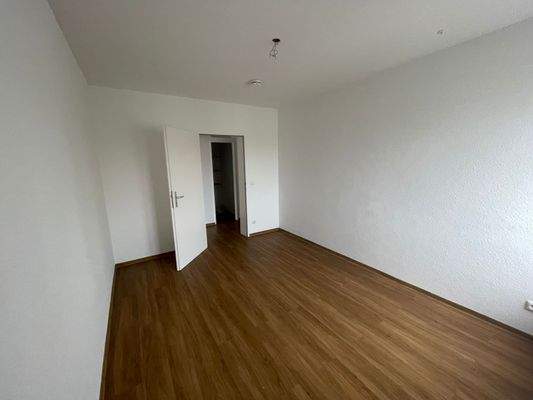 Schlafzimmer, brauner Laminatfußboden und weiß gestrichene Wände