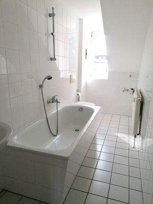 gefliestes Bad mit Wanne und Fenster