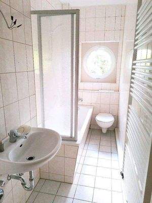gefliestes Bad mit Wanne und Fenster