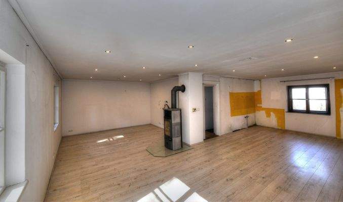 Blick ins große Eck-Wohnzimmer mit Kaminofen sowie Küche