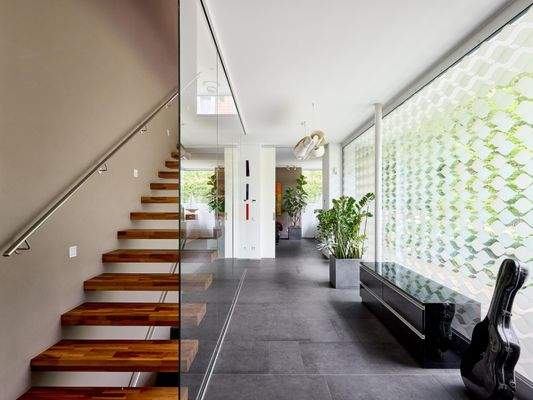 Der Empfangsbereich präsentiert sich lichtdurchflutet; die freitragende Treppe setzt die Transparenz der Fensterflächen elegant fort