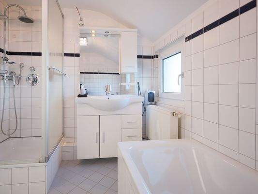 Hell gefliestes Tageslichtbadezimmer mit Badewanne und Dusche