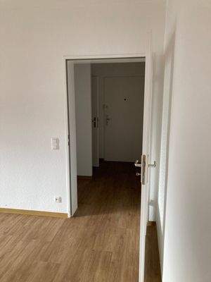 Wohnzimmer mit PVC-Bodenbelag in Holzoptik und Blick zum Flur