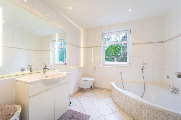 Modernes Vollbad mit Fliesenbelag im linken Flügel