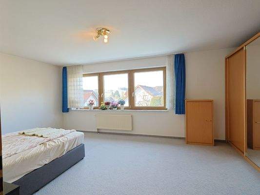 Geräumiges, helles Schlafzimmer im OG mit Ausblick auf nahegelegene Wiesen