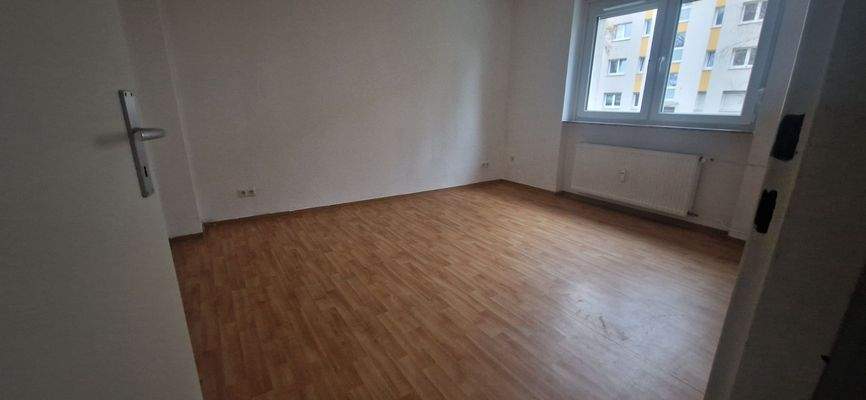 Schlafzimmer/Wohnzimmer mit PVC-Bodenbelag in Holzoptik mit tapezierten Wänden.