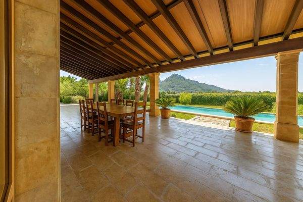 Überdachte Terrasse mit großem Esstisch und Bergblick