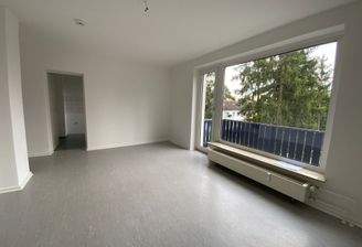 Wohnzimmer mit großem Fenster und Glastür mit Zugang zum Balkon.JPG