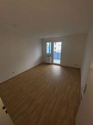 Schlafzimmer mit braunem PVC Boden, weißen Wänden, Fenster und Balkontür.jpg