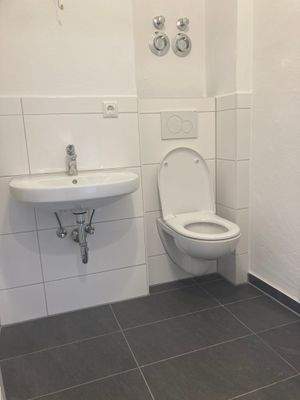 Badezimmer (neu) mit modernen, hellen Wand- und dunklen Bodenfliesen