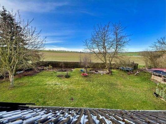 Blick aus dem Dachfenster über den Garten hinweg Richtung Feld
