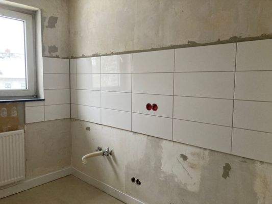 Küche mit weißem Fenster, weißem Fliesenspiegel und weißer Heizung.