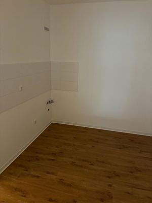 Küche ohne Fenster. Wände und Decke weiß gestrichen. Neuer Fliesenspiegel und Vinylboden in braun.