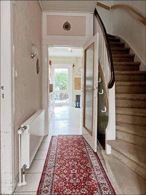 Gefliester Eingangsbereich mit Treppenhaus