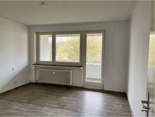 Schlafraum mit Zugange zum Balkon, helle Wände und hellgrauer Bodenbelag in Holzoptik.JPG