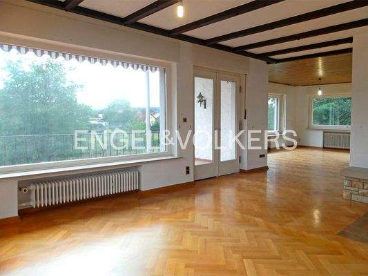 Wohnzimmer mit Panoramafenster und angrenzendem Balkon
