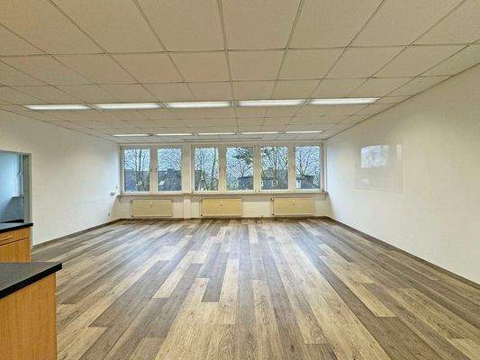 großer Arbeitsraum mit Fenstern zur Wohnbebauung und Feldern