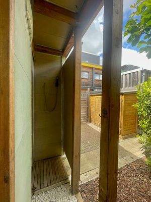 begehbare Außendusche mit Fahrradschuppen im Hintergrund