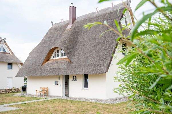 Außenansicht des reetgedeckten Ferienhauses „Wiesenpieper“