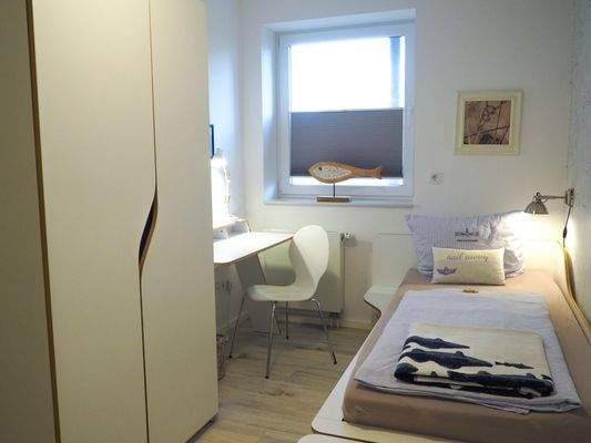 UG Gästezimmer mit Einzelbett, Schrank und Schreibtisch in hellen Farben