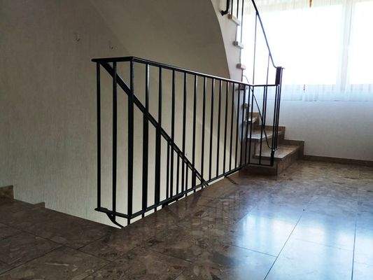 Treppenhaus mit Steinfußboden und Eisengeländer