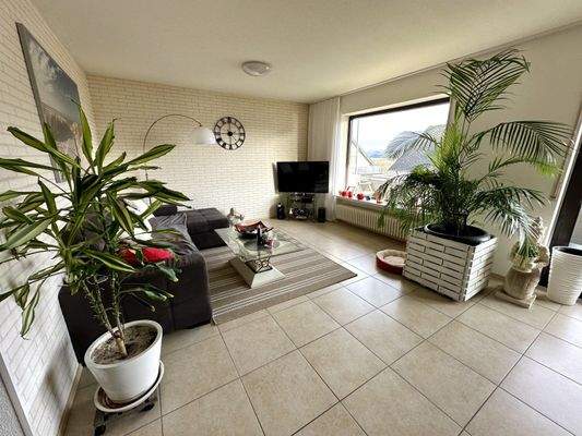 Lichtdurchflutetes Wohnzimmer mit Panoramafenster und eleganter Naturstein-Optik