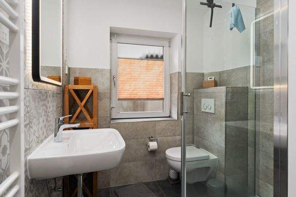 Tageslichtbad (5,87m²) mit verglaster Eckdusche und Handtuchheizung.