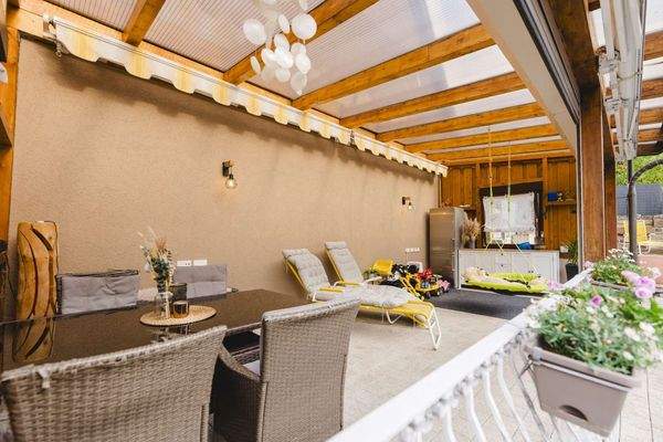 Überdachte Outdoor Lounge mit warmem Ambiente und Platz zum Wohlfühlen.