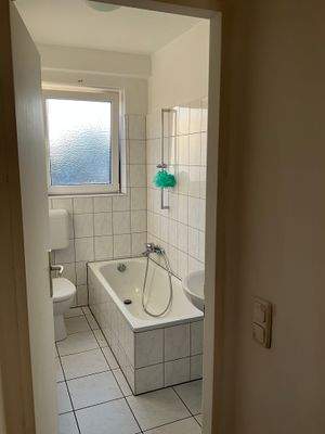 Blick in das Badezimmer. Boden und Wände mit weißen Fliesen. Deckenflächen weiß angelegt. Fenster vorhanden