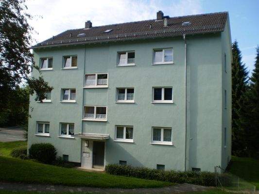 Vorderansicht (Eingangsbereich) eines alleinstehenden 6-Parteienhauses in grüner Umgebung