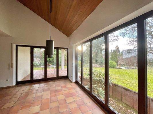 Die bodentiefen Fenster lenken den Blick in den Garten und auf die überdachte Terrasse
