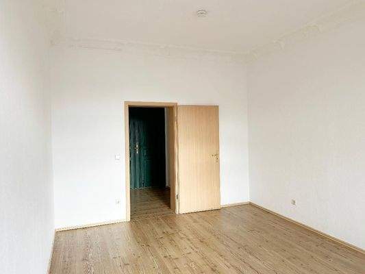 Schlafzimmer mit Stuckdecke und Blick Richtung Flurbereich