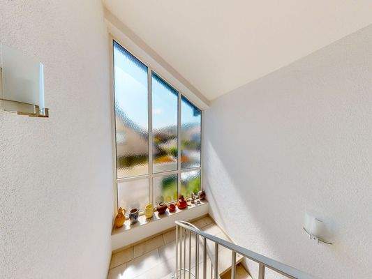 Treppenhaus mit großzügiger Fensterfront.