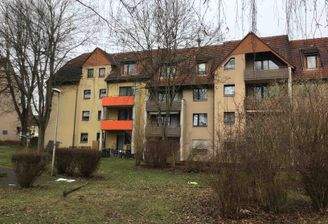 T.-Heuss-Allee 11, Außenansicht mit Blick über den begrünten Innenhof auf die Balkonseite eines mehrgeschossigen Wohngebäudes in Reihenbebauung.